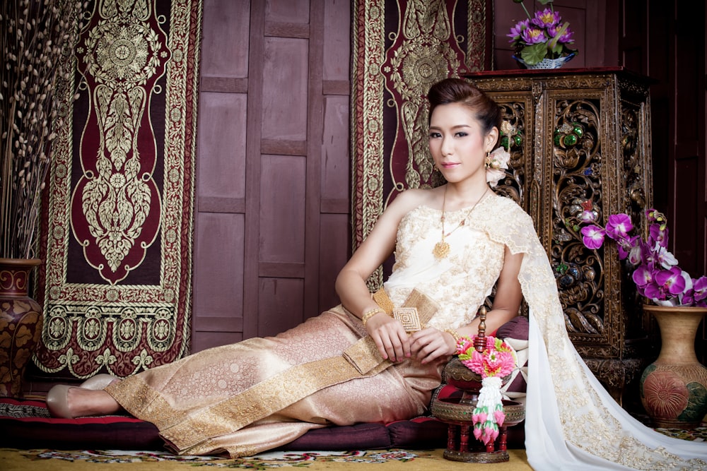woman lying in floor while wearing gold traditional dress