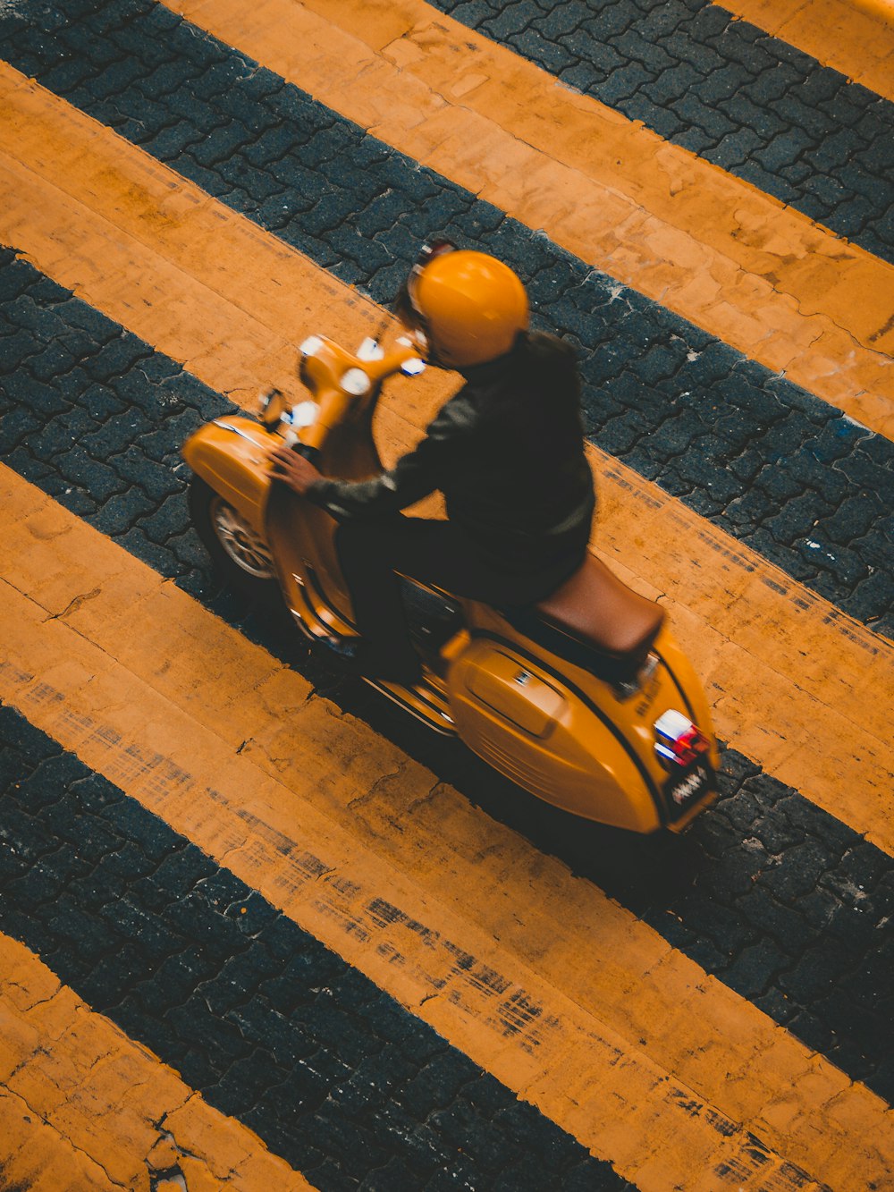 Uomo che guida su un motorino giallo su linee gialle a strisce