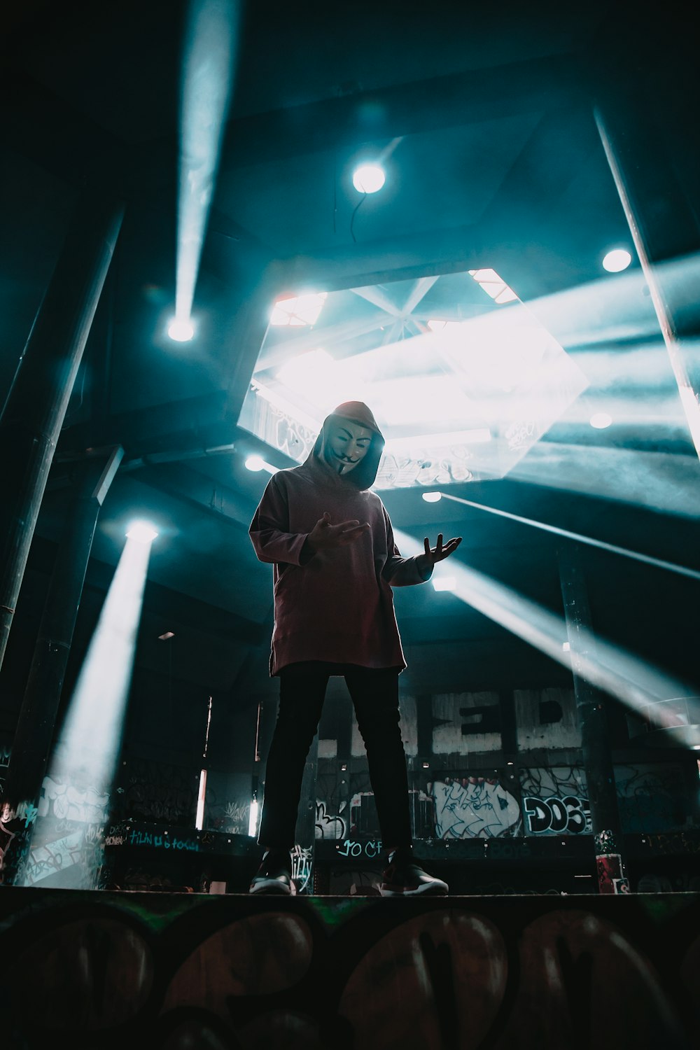 man wearing Guy Fawkes mask standing on stage