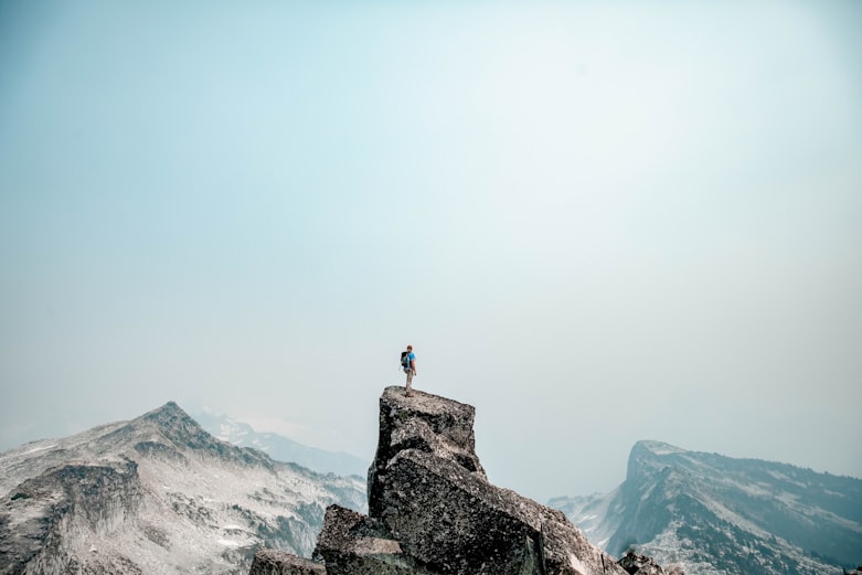 A hiker triumphantly standing at the summit of a mountain