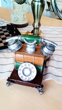 A chic vintage telephone on a glossy black table beside a single white rose in a crystal vase, reflecting Glam Australia's timeless elegance.