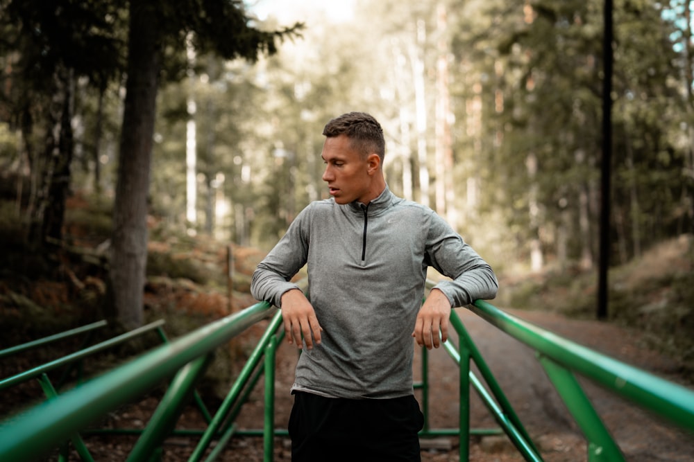 man in gray sweater standing in middle of two green steel frames