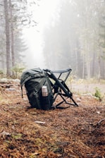 black and gray backpack with camping chair on forest