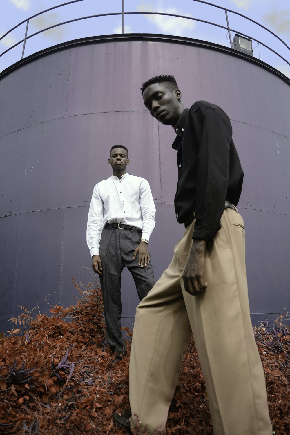 two men standing on red flower in front of gray metal wall