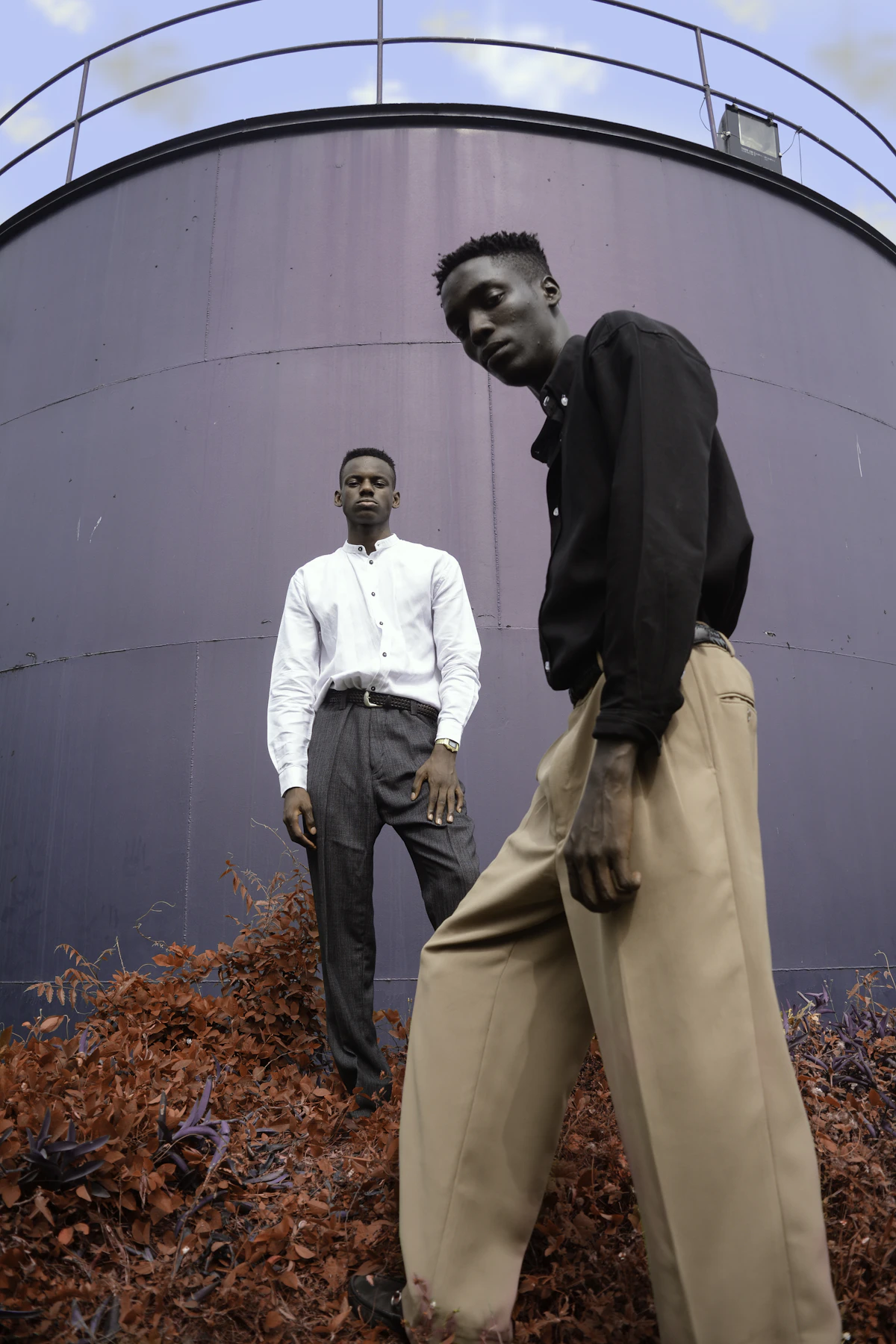 Two men in button-down shirts and wide pleated trousers