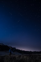 A person studying a handmade map under the stars at night.