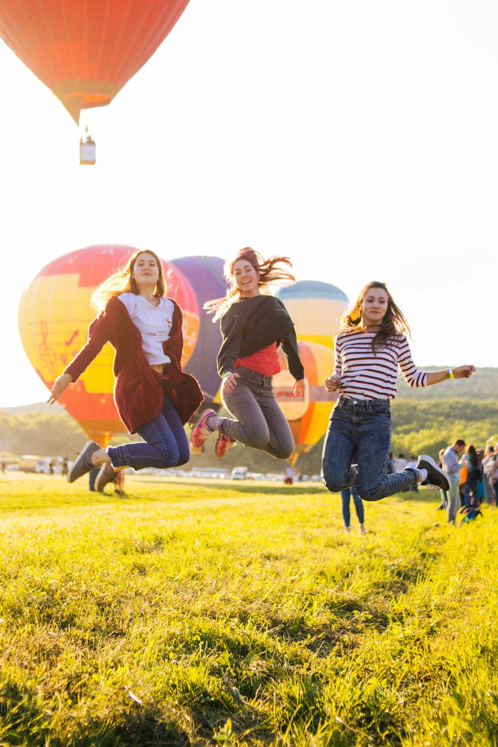 three women jumping above green grass