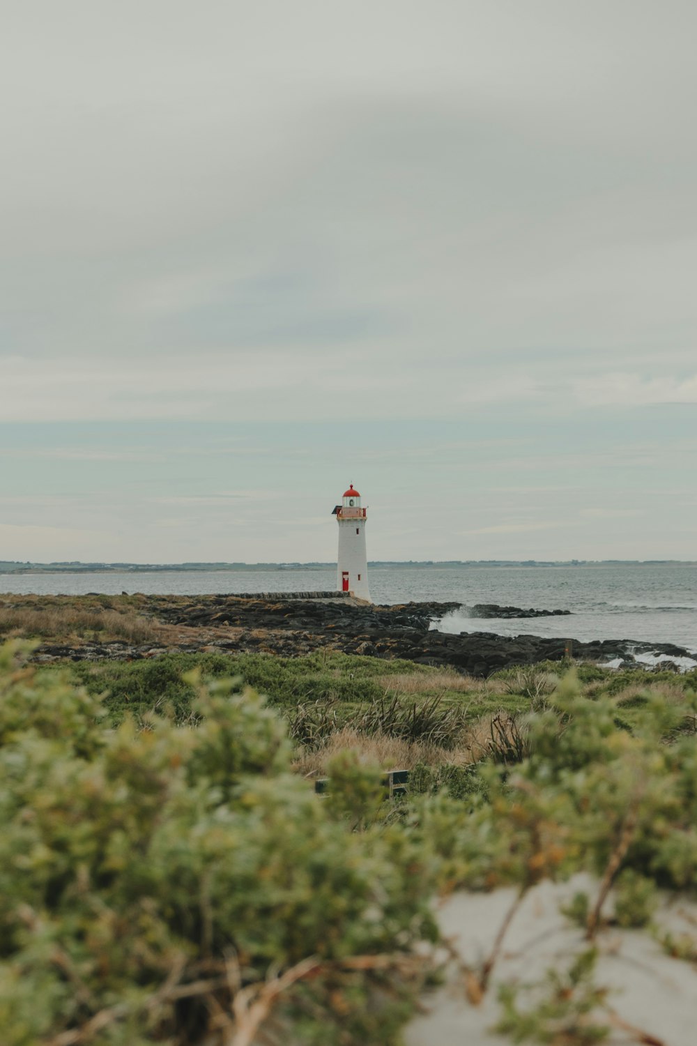 Weißer Leuchtturm in der Nähe des Meeres während des Tages
