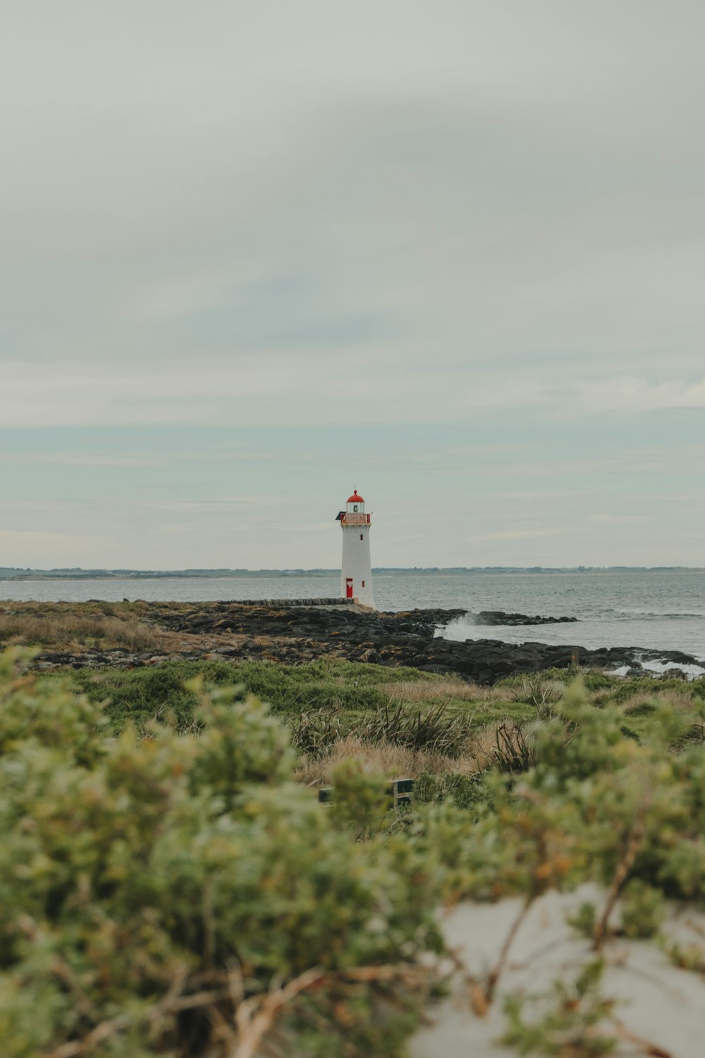 Phare blanc près de la mer pendant la journée