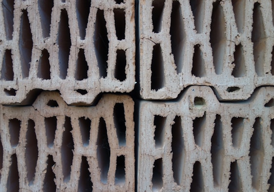 Photo of a stack of various sized concrete blocks with steel rods and cement bags in the background at Vasista Building Blocks facility.