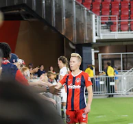 Tim Payne interacting with fans after a match, smiling and signing autographs.