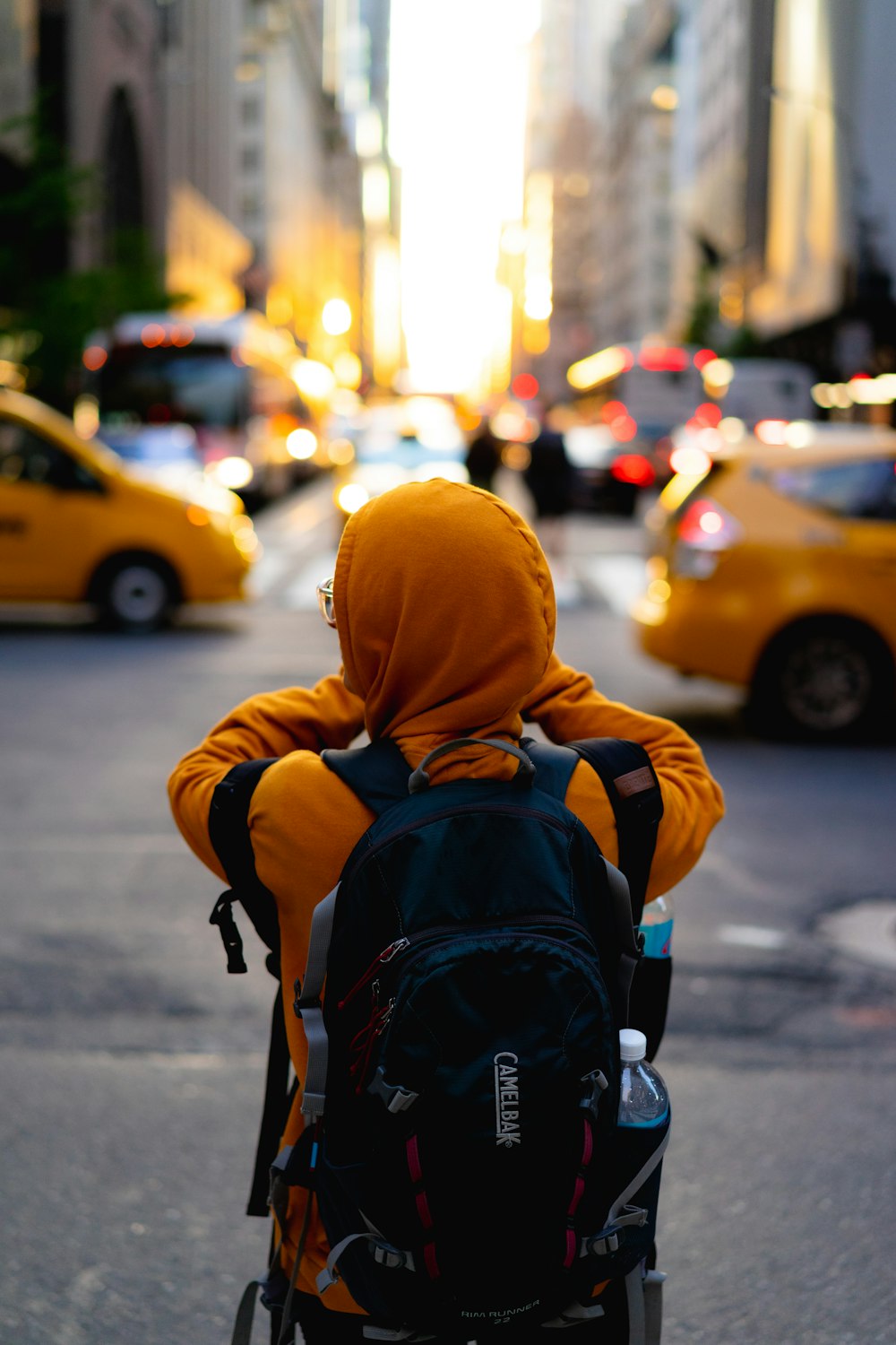 person in orange hoodie carrying black backpack