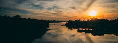 Sunset casting warm hues over a calm river, reflecting peaceful energy.