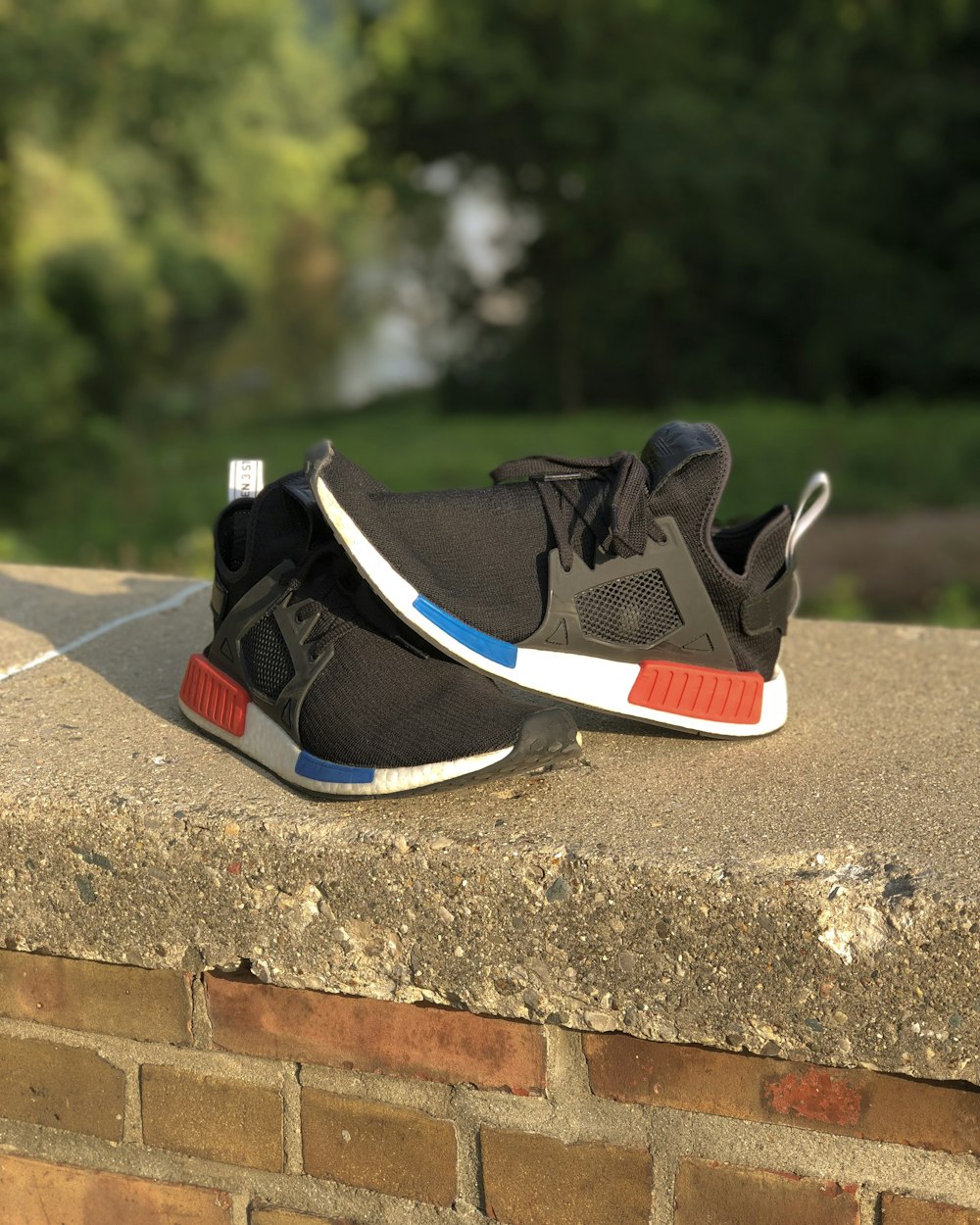 pair of black-and-white adidas NMD on gray concrete fence