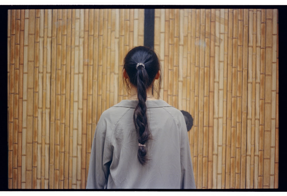 woman wearing gray top facing wooden wall