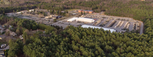 A sleek aerial shot of a biochar production facility nestled in a lush forest, showcasing industrial precision amid nature.