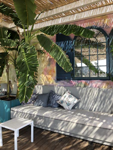 A sunlit patio featuring verdeluxe's HDPE sectional sofa adorned with colorful outdoor throw pillows and lush green wall planters.