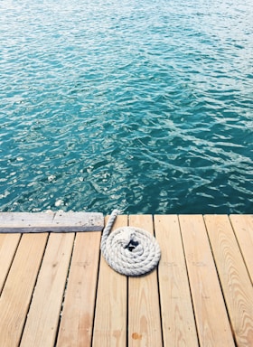 Close-up of durable nautical ropes coiled neatly on a wooden dock under warm sunlight.