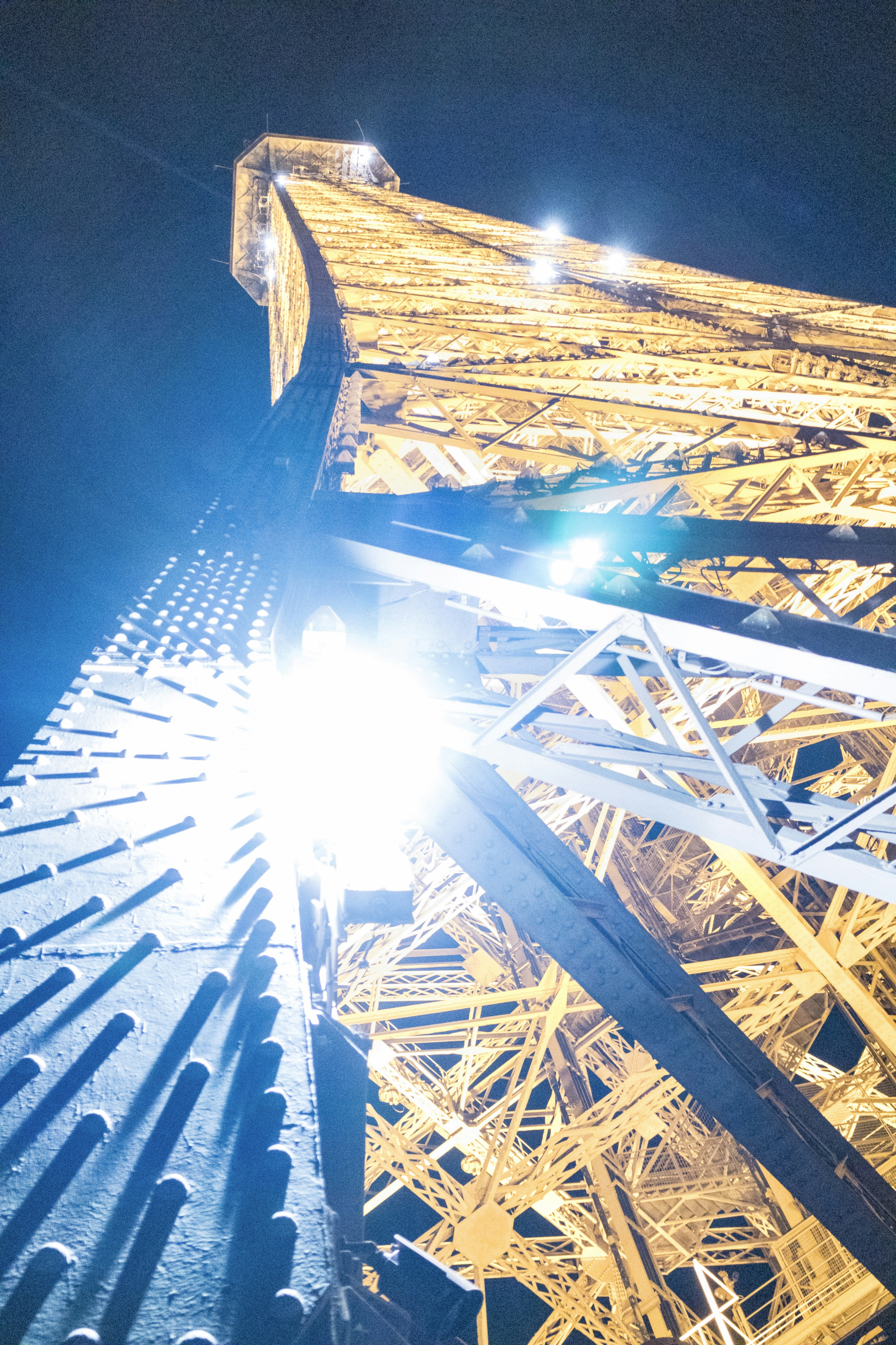 Tour Eiffel illuminée la nuit, ciel sombre bleu profond avec reflets dorés sur la Seine