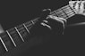 grayscale photo of person holding guitar neck and strings