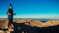 A person wearing Wild sunglasses standing on a mountain peak with a vast horizon behind.