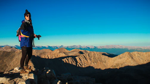 Person wearing Wild sunglasses standing on a mountain trail with a vast landscape behind.
