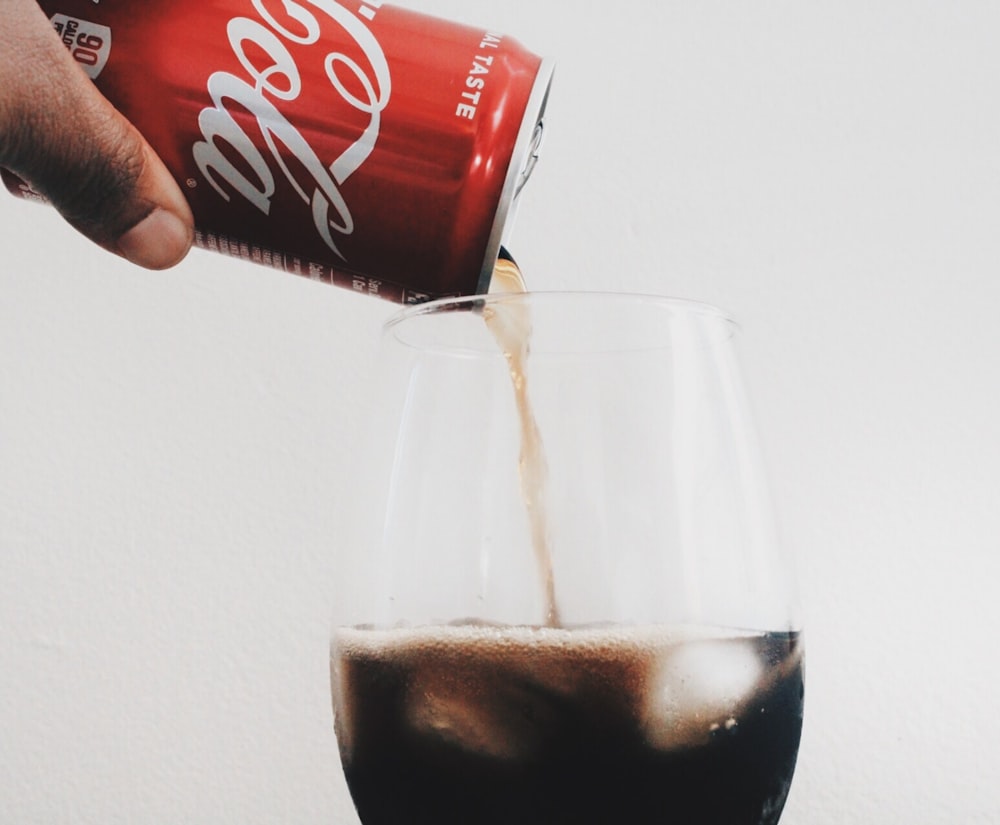 time lapse photography of person pouring can of Coca-Cola in wine glass