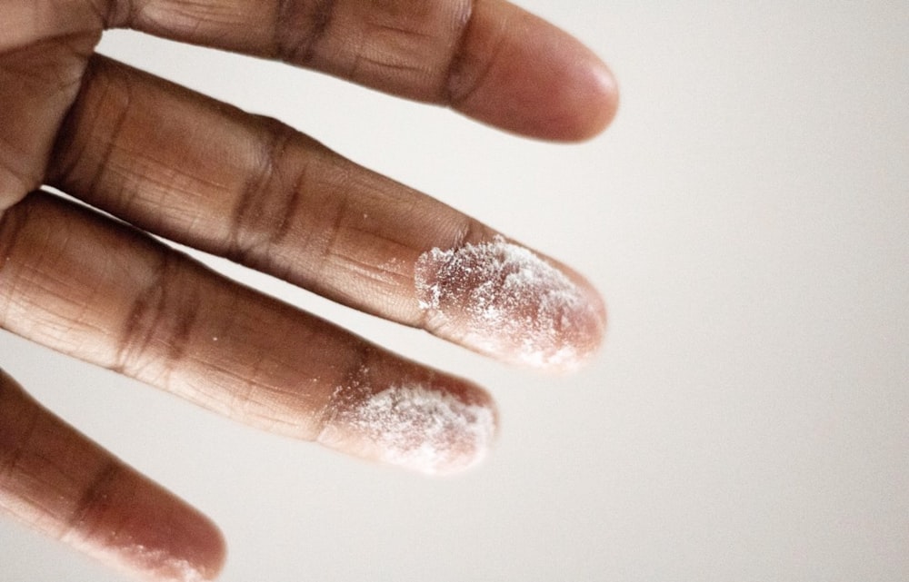 白い粉を塗った人の指のクローズアップ写真