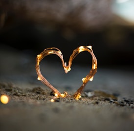 close-up photography of heart shaped fairy lite on brown sand