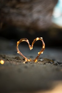 close-up photography of heart shaped fairy lite on brown sand