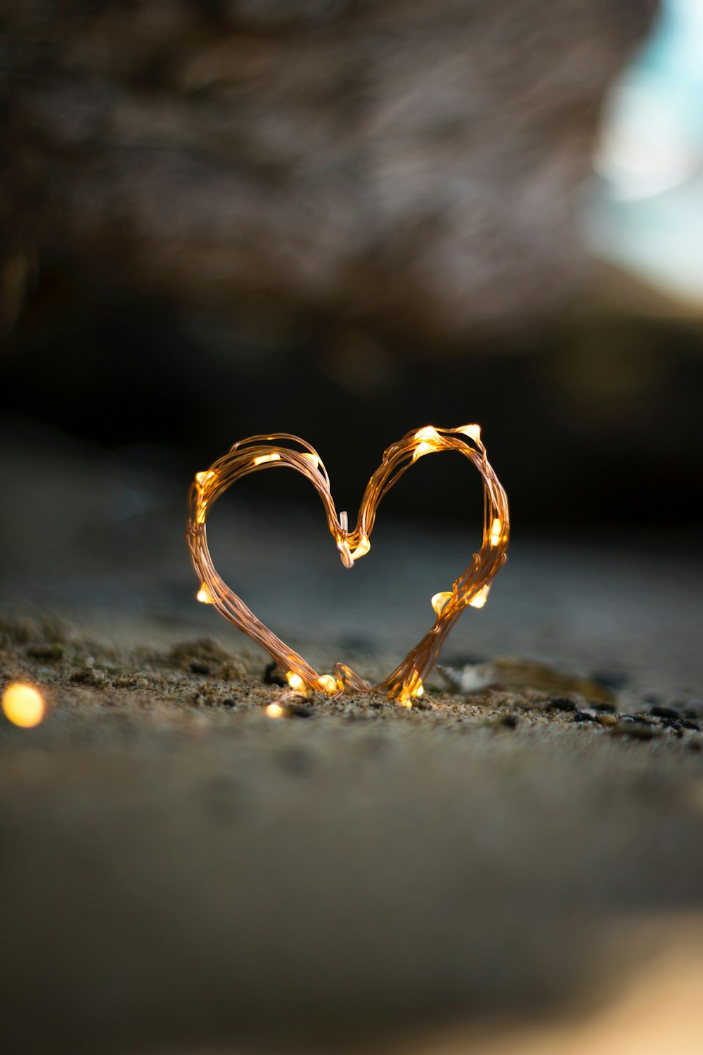 Fotografia ravvicinata di Fairy Lite a forma di cuore su sabbia marrone