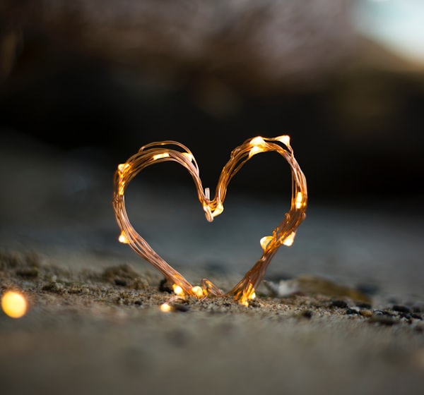 close-up photography of heart shaped fairy lite on brown sand