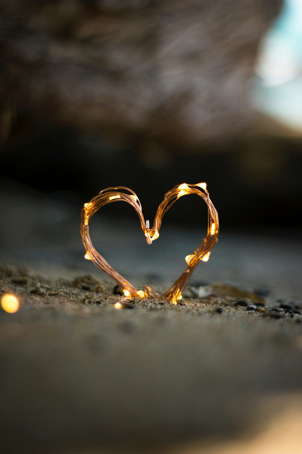 close-up photography of heart shaped fairy lite on brown sand