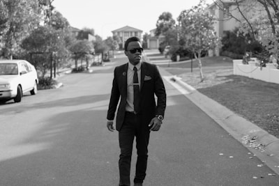 A process server walking confidently through a residential neighborhood with documents in hand.