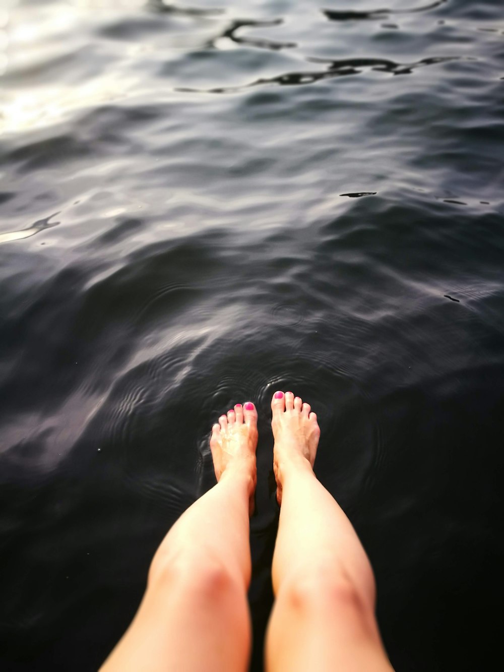 person feet on calm body of water