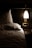 A cozy, dimly lit bedroom features a neatly made bed with white pillows and sheets. A small bedside table holds a few items, illuminated by a modern wall-mounted lamp casting a warm glow. The setting suggests a quiet, intimate atmosphere suited for relaxation and rest.