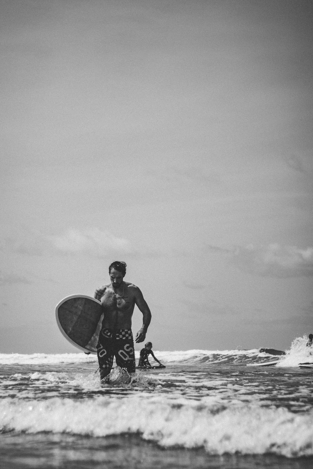 homem em pé na praia segurando prancha de surf