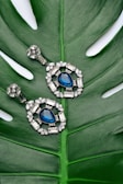 pair of silver-colored earrings with blue gemstone