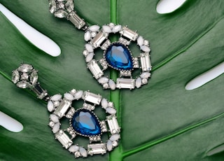 pair of silver-colored earrings with blue gemstone