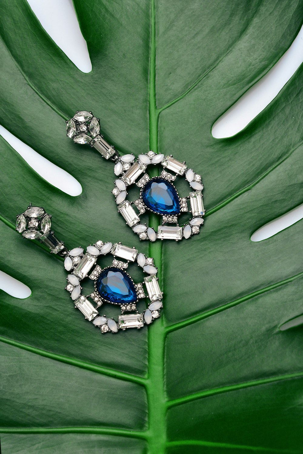 pair of silver-colored earrings with blue gemstone
