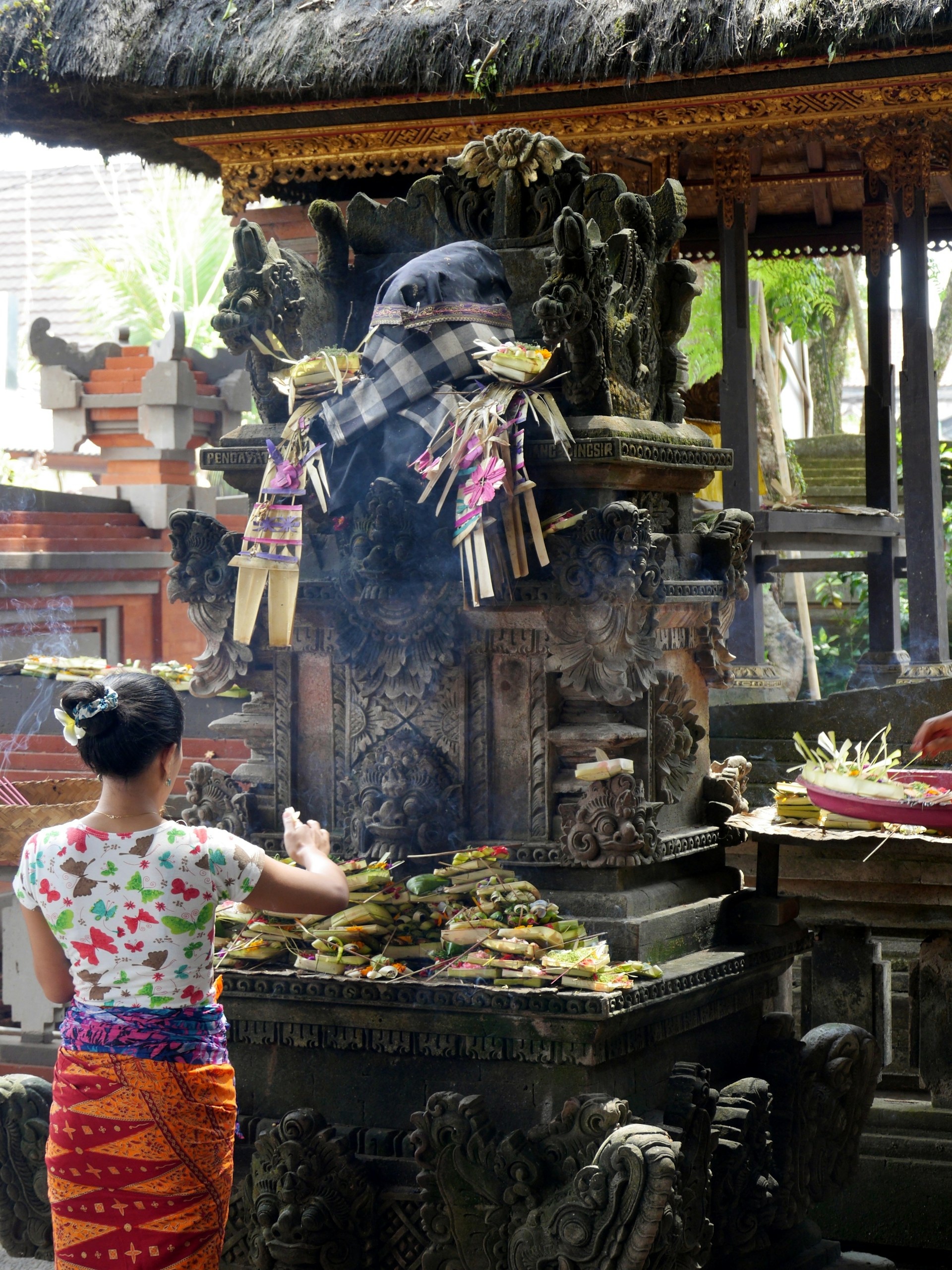 A peaceful scene at a sacred temple in Ubud, with offerings laid out and colorful decorations fluttering in the breeze.