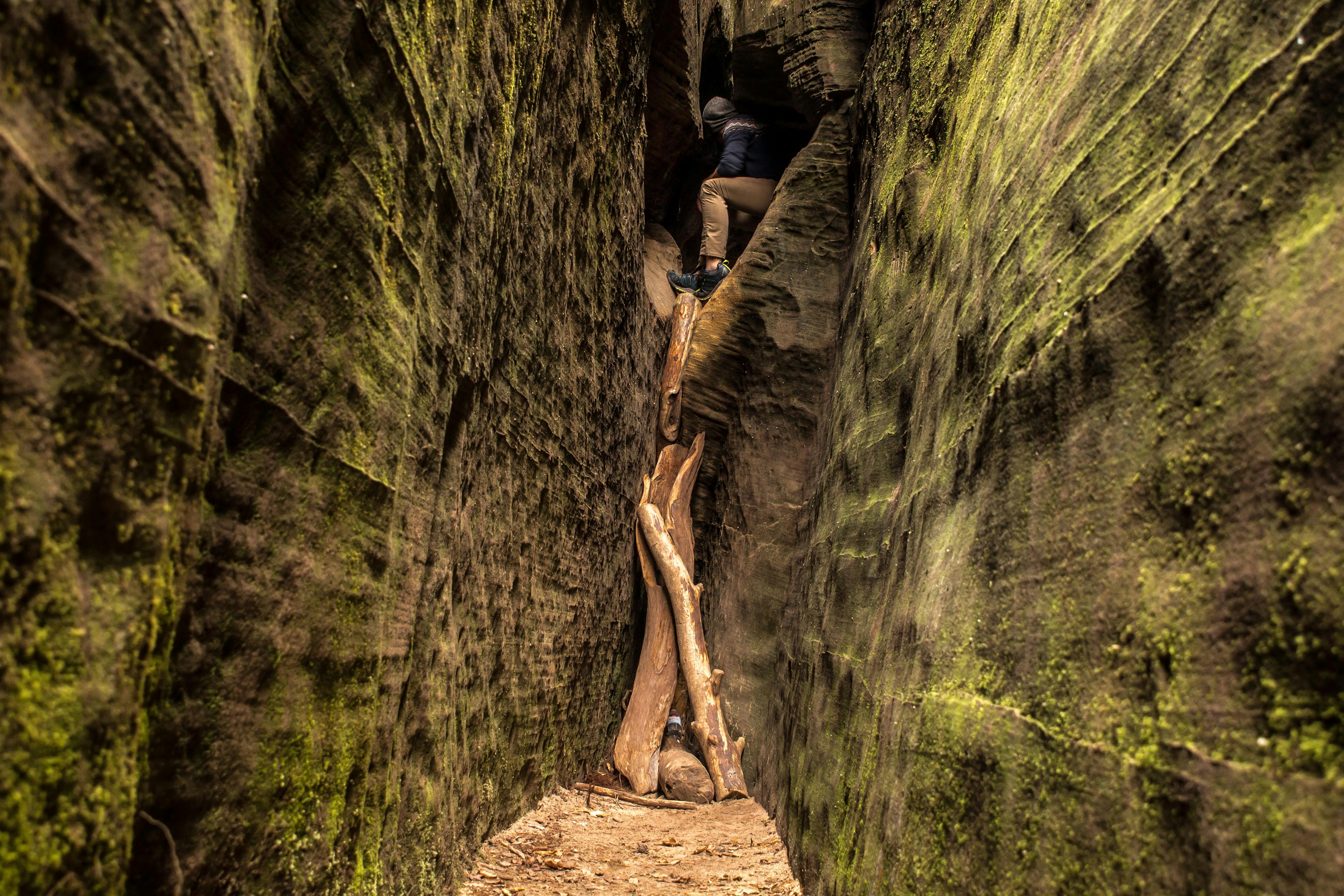 man inside cave between narrow pathway