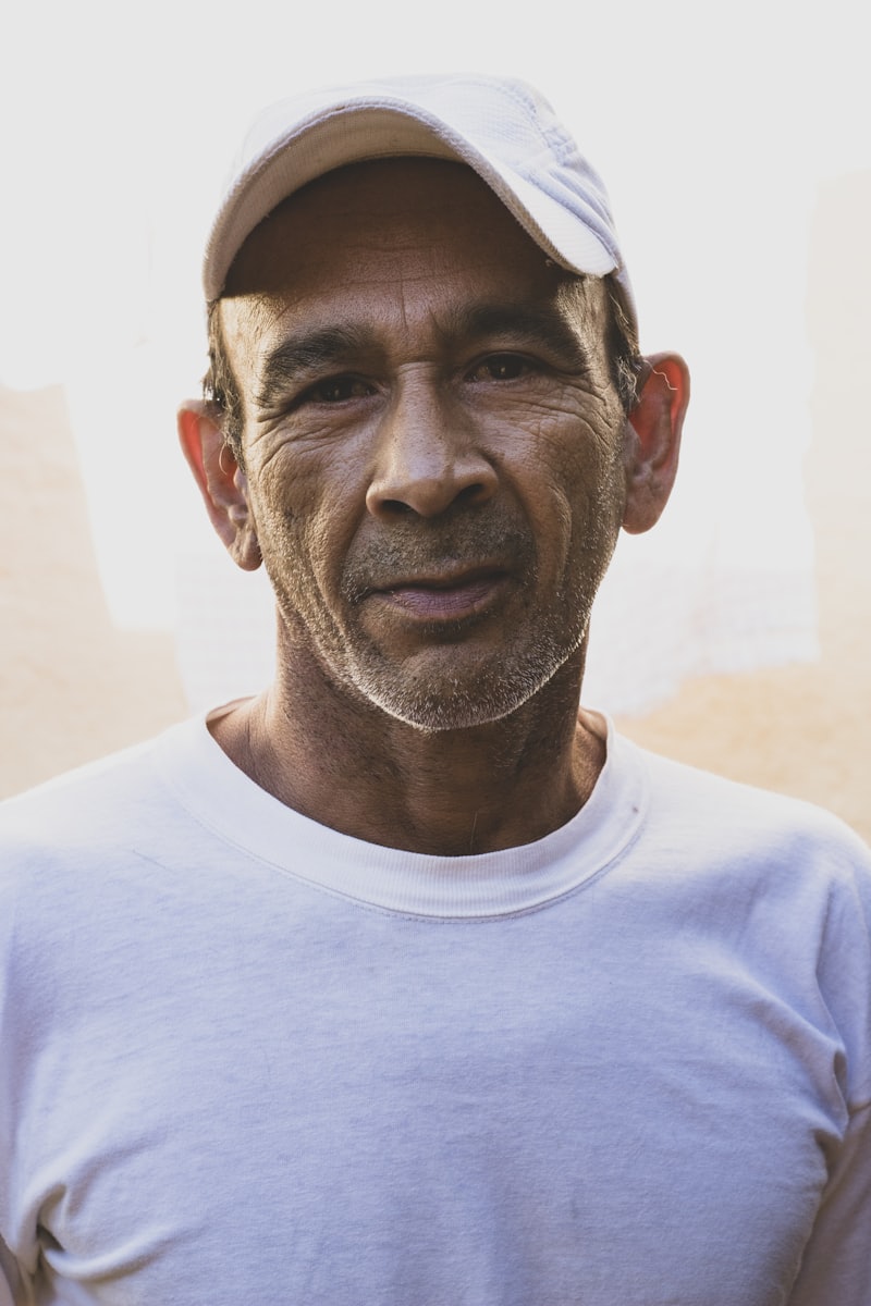Hombre con gorra blanca y camiseta blanca mirando a la cámara