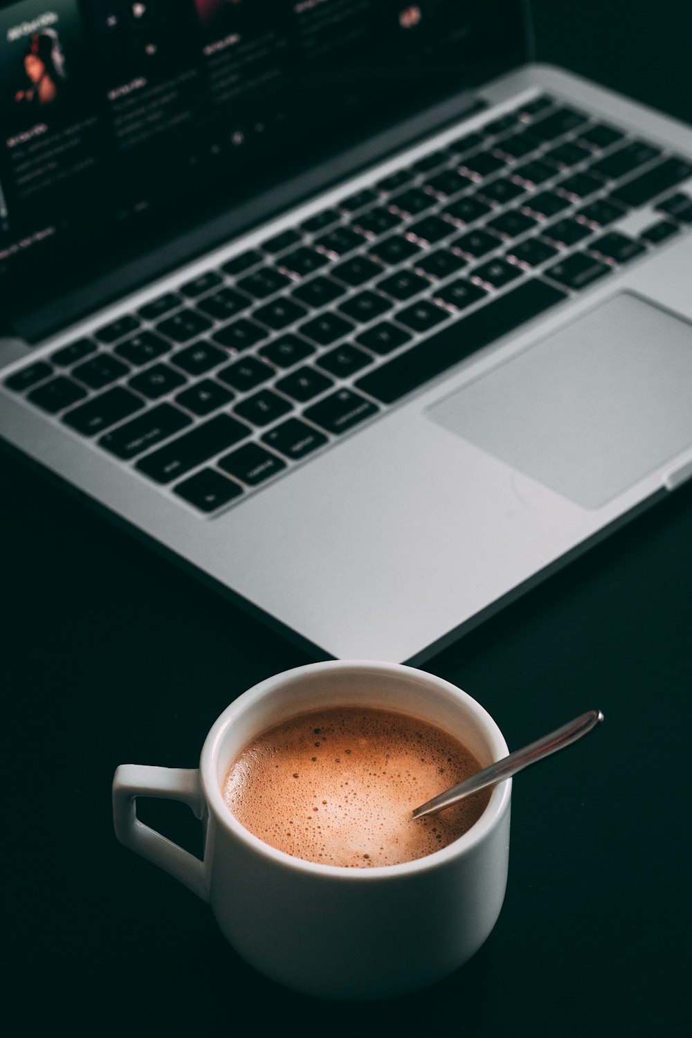 MacBook Pro near white teacup