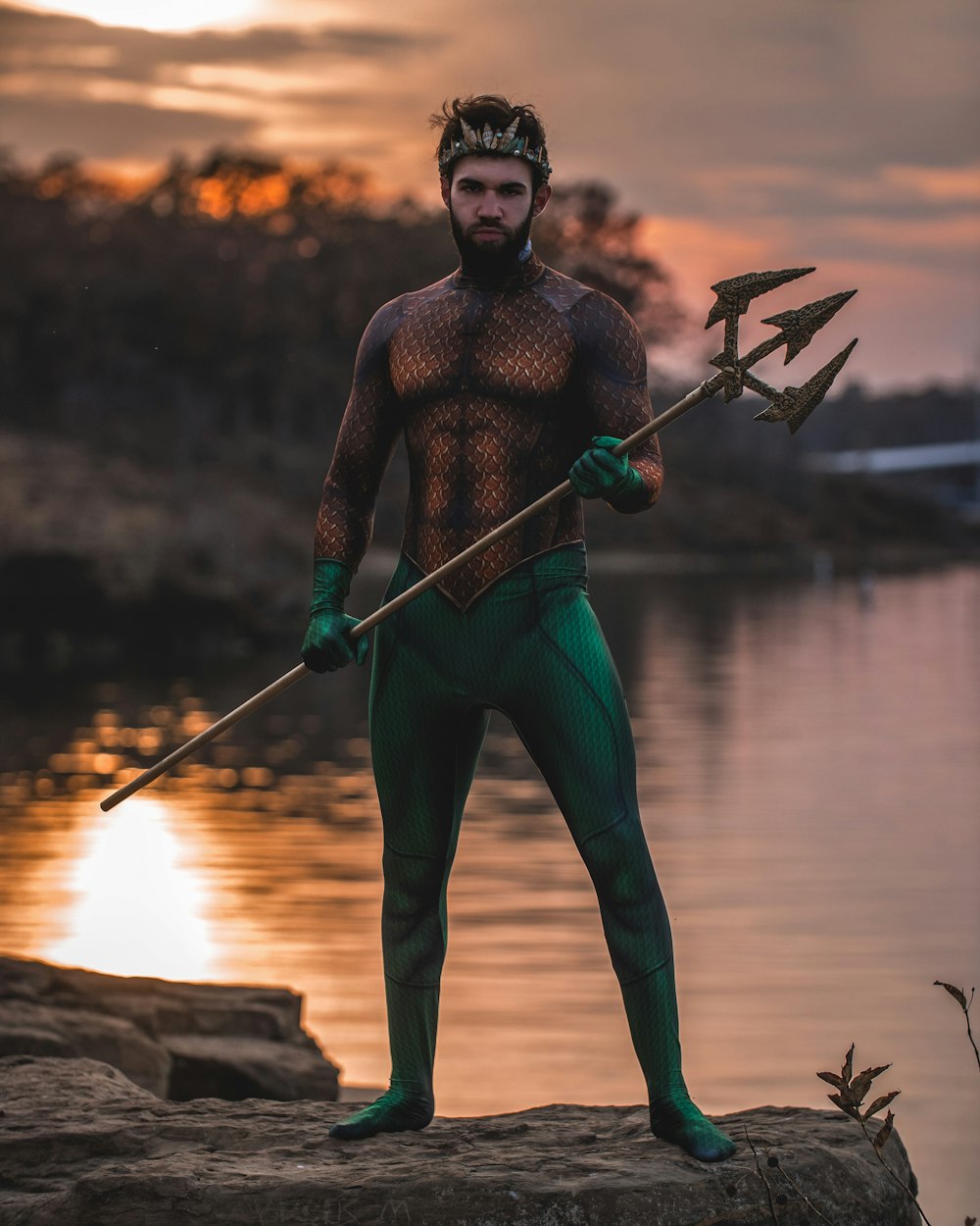man wearing Poseidon costume standing on rock
