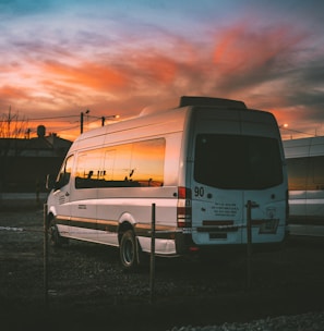 white Mercedes-Benz Sprinter parked on open yard beside chain rail