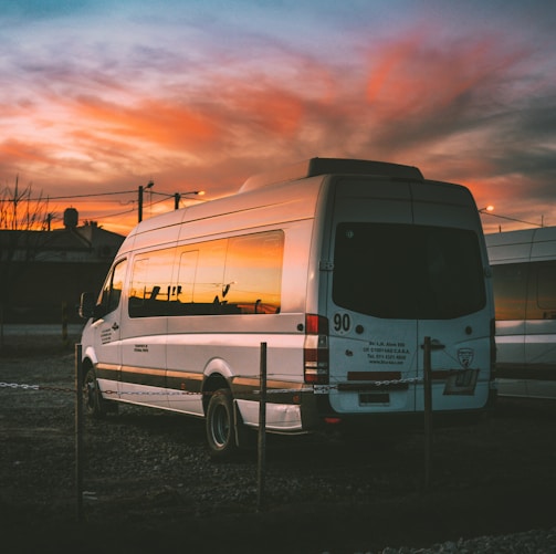 white Mercedes-Benz Sprinter parked on open yard beside chain rail