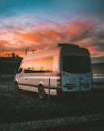 white Mercedes-Benz Sprinter parked on open yard beside chain rail