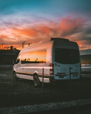 white Mercedes-Benz Sprinter parked on open yard beside chain rail