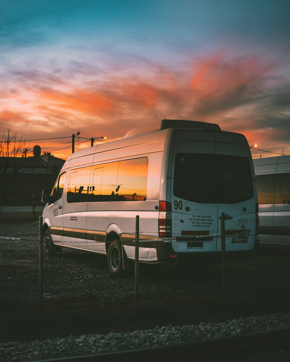 white Mercedes-Benz Sprinter parked on open yard beside chain rail